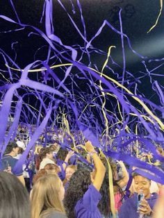 a group of people standing around each other with purple streamers in the air above them