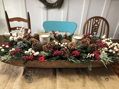 a wooden sleigh filled with pine cones, berries and candles on top of a table