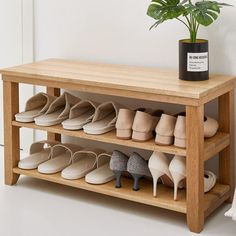 a wooden shoe rack with several pairs of shoes on it next to a potted plant