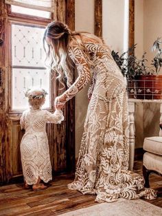 a mother and her daughter standing in front of a window