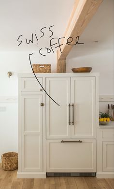 a kitchen with white cabinets and wood flooring next to a wooden beam on the ceiling