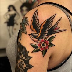 a woman's shoulder with a bird and flowers tattoo on her left upper arm