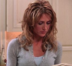 a woman with long hair sitting in a chair looking at something on the table next to her