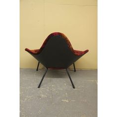 a black and red chair sitting on top of a cement floor next to a yellow wall