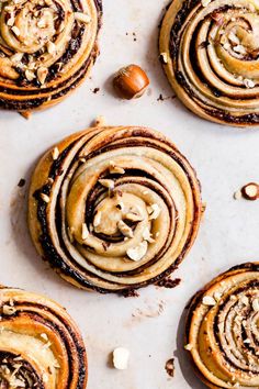 several cinnamon rolls with nuts on top of a baking sheet and one has been cut in half to show the filling