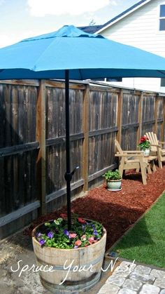 an outdoor patio area with a blue umbrella and flower pots on the side of it