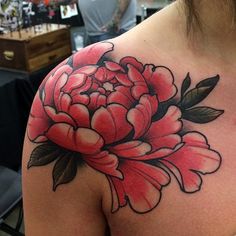 the back of a woman's shoulder with pink flowers on it and green leaves