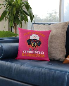 a pink pillow with a black dog wearing a white hat on it sitting on a blue couch