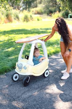 a woman pushing a small car with a baby in it