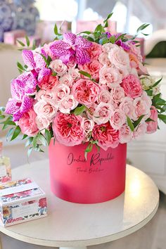 a pink flower pot sitting on top of a table next to a box of chocolates