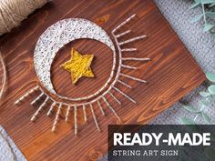 the string art is made to look like a crescent moon and star on a wooden board