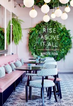 the inside of a restaurant with pink booths and green plants hanging from the ceiling above