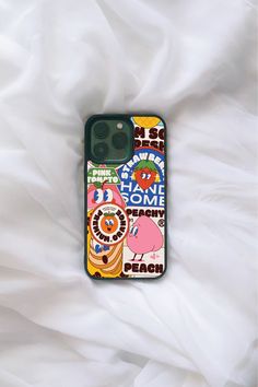 an iphone case with some stickers on it sitting on top of a white sheet