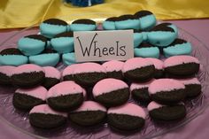 a plate full of cookies with pink, blue and black frosting on them that say wheels