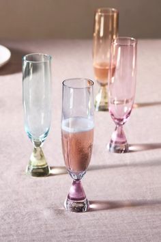 three different colored glasses sitting on top of a table next to plates and utensils