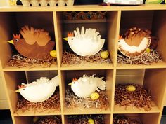 the shelves are filled with fake birds and nested eggs in cardboard boxes on top of hay