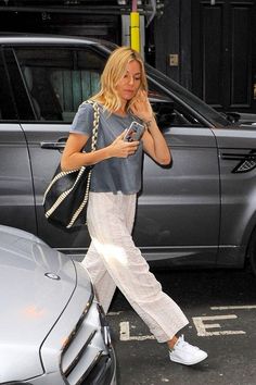 a woman is walking down the street while talking on her cell phone and holding a purse