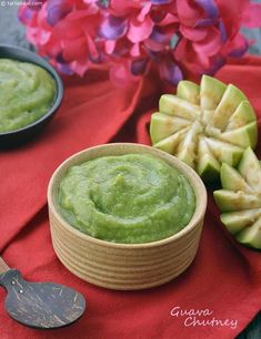 a bowl of guacamole next to some cut up apples on a red cloth