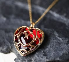 a red heart shaped pendant sitting on top of a rock