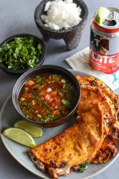 mexican food on a plate with salsa and limes