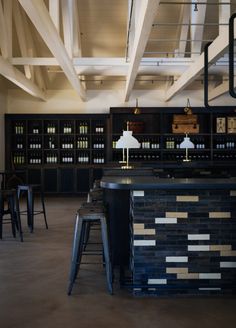 an empty bar with stools and tables in the center, under a vaulted ceiling