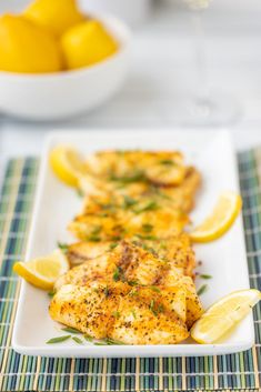 a white plate topped with chicken covered in lemon wedges and garnished with herbs