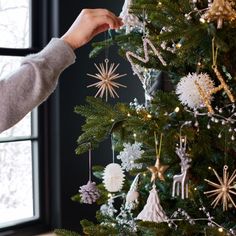 a person decorating a christmas tree with star shaped ornaments on the top and bottom