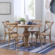 a dining table with four chairs and a rug on the floor in front of it