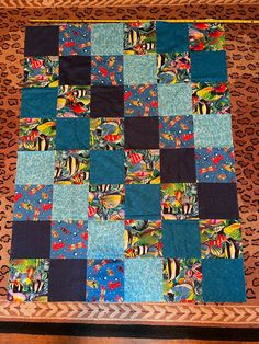 a patchwork quilt is laying on top of a leopard print tablecloth with blue and black squares