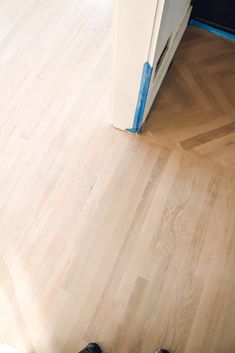 a pair of black shoes sitting on top of a wooden floor next to a refrigerator