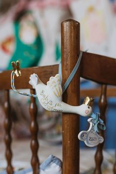 a toy bird hanging from the side of a wooden chair