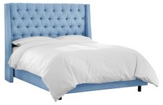 a bed with a blue headboard and white sheets