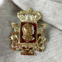 "Lovely Coro gold tone cameo-look pin in the shape of a crest from the 1940s. Crown on top, with the royal  greyhound dog on each side and a layered cameo of a knight or centurion in the center. Marked with Coro in a heavier italic script.  SIZE 1 5/8\" tall\" x 1 1/4\"  wide CONDITION Gently used.  Part of an incredible crown brooch collection that was collected over 40 years. You can see more of this fabulous collection in our online store. This is a pre-owned item. It has been used and loved Vintage Gold Brooches For Ceremonial Use, Vintage Formal Coat Of Arms Jewelry, Vintage Medallion Brooches For Formal Occasion, Gold Brooch With Vintage Charm For Collectors, Antique Gold Lapel Pin Collectible, Antique Gold Enamel Pin For Formal Occasions, Vintage Gold Brooch Lapel Pin, Vintage Style Formal Brooch Enamel Pin, Vintage Formal Enamel Pin Brooch