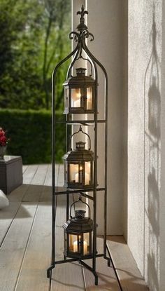 a tall metal candle holder sitting on top of a wooden floor next to a window