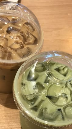 two plastic cups filled with ice cream on top of a wooden table