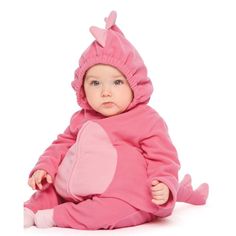 a baby in a pink costume sitting on the floor with her legs crossed and head turned to the side