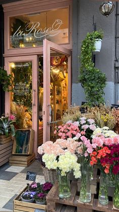 many vases filled with flowers sitting in front of a flower shop