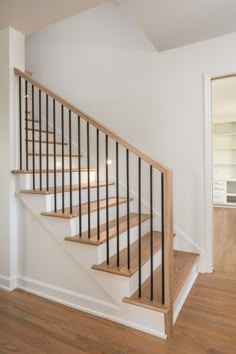 an empty room with stairs and hard wood flooring