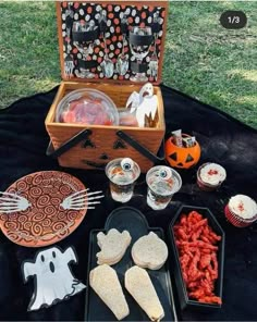 an open trunk filled with halloween treats on a black tablecloth covered in plastic cups