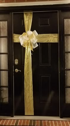 a black door with a yellow ribbon on it and a cross hanging from the side