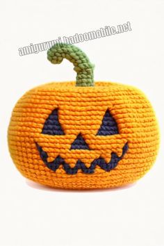 an orange knitted pumpkin with a green cord in the shape of a jack - o'- lantern