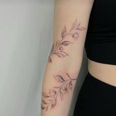 a woman's arm with flowers and leaves tattooed on the left side of her arm