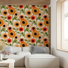 a white couch sitting in front of a wall covered in orange and black flowers on it