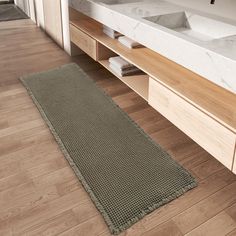 a bathroom with two sinks and a large rug on the floor in front of it