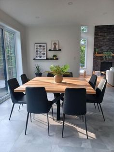 a dining room table with black chairs and a potted plant