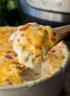 a spoon full of cheese being lifted from a casserole dish