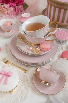 a table topped with plates and cups filled with pink decorations