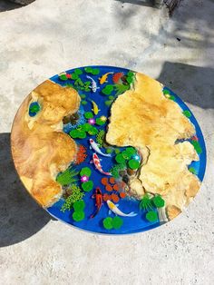 a blue plate with yellow and green designs on it sitting on the ground next to a tree