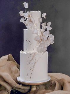 a three tiered white cake with flowers on the top and bottom, sitting on a table