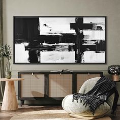 a black and white painting hanging on the wall next to a chair in a living room